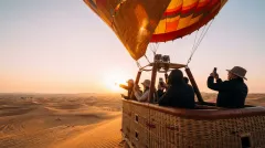 Guests standing in the balloon basket as it climbs at first light